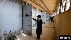 Hayat al-Turki, 27, looks at a cell inside Sednaya prison, which was known as a slaughterhouse under Syria's Bashar al-Assad rule, hoping to find her relatives, in Sednaya, Dec. 11, 2024.