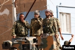FILE - Members of Syrian National Army, known as Free Syrian Army, stand on top of an armored vehicle in the Turkish border town of Ceylanpinar in Sanliurfa province, Turkey, Oct. 11, 2019.