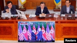 South Korean President Moon Jae-in looks at a TV broadcasting a news report on summit between the U.S. and North Korea during a cabinet meeting at the Presidential Blue House in Seoul, South Korea, June 12, 2018. 