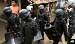 Para anggota Densus 88 membawa perlengkapan dan senjata mereka setelah melakukan penggerebekan di rumah yang ditempati oleh militan di Kabupaten Bandung, sebagai ilustrasi. (Foto: AP)