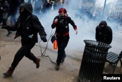 Activists run after being hit by a stun grenade while protesting against U.S. President Donald Trump on the sidelines of the inauguration in Washington, DC, U.S., January 20, 2017. REUTERS/Adrees Latif
