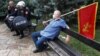 Policajci na Cetinju sjede pored čovjeka sa crnogorskog zastavom tokom protesta protiv ustoličenja mitropolita Joanikija u crnogorskoj prijestonici (Foto: Rojters/Stevo Vasiljevic)