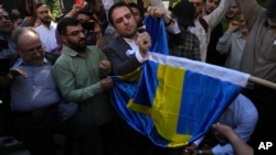 Waandamanji wa Iran wakichoma bendera ya Sweden baada ya Quran kuchomwa Sweden wakati wa maandamanaji