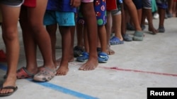 FILE - Venezuelan migrant children line up inside a coliseum where a temporary camp has been set up, after fleeing their country due to military operations, according to the Colombian migration agency, in Arauquita, Colombia, March 26, 2021.
