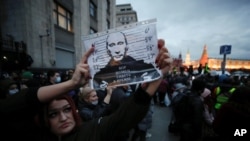 ស្ត្រីម្នាក់កាន់រូបប្រធានាធិបតីរុស្ស៊ីលោក Vladimir Putin ក្នុងការតវ៉ាប្រឆាំងរដ្ឋាភិបាលរុស្ស៊ី ពាក់ព័ន្ធនឹងការឃុំខ្លួនមេដឹកនាំបក្សប្រឆាំងលោក Alexie Navaly នៅទីក្រុងមូស្គូ រុស្ស៊ី កាលពីថ្ងៃទី ២១ ខែមេសា ឆ្នាំ ២០២១។