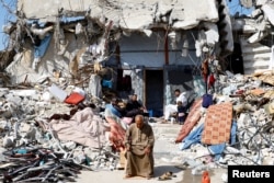 Palestinians sit amidst the rubble of buildings destroyed during the Israeli offensive, amid a ceasefire between Israel and Hamas, in Rafah in the southern Gaza Strip, Feb. 16, 2025.