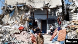 Palestinians sit amidst the rubble of buildings destroyed during the Israeli offensive, amid a ceasefire between Israel and Hamas, in Rafah in the southern Gaza Strip, Feb. 16, 2025.