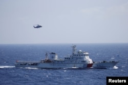 FILE - Chinese ship and helicopter are seen during a search and rescue exercise near Qilian Yu subgroup in the Paracel Islands, which is known in China as Xisha Islands, South China Sea, July 14, 2016.
