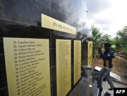FILE - Workers mount a plaque at a memorial for the victims of last year's terrorist attack that killed 148 people at the campus of Garissa University College, April 2, 2016.
