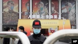 រូបឯកសារ៖ សន្តិសុខចិនមួយរូបដែលមានពាក់ម៉ាស់ កំពុងយាមល្បាតច្រកទ្វារចូលទីតាំងពិពរណ៍មួយដែលក្រុមអ្នកជំនាញរបស់អង្គការសុខភាពពិភពលោកកំពុងទស្សនកិច្ច នៅទីក្រុងវូហាន ខេត្ត Hubei ប្រទេសចិន កាលពីថ្ងៃទី ៣០ ខែមករា ឆ្នាំ ២០២១។