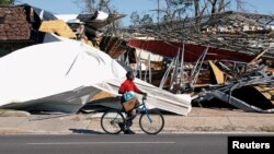 A man carries food and water past a building damaged by Hurricane Michael in Parker, Fla., Oct. 13, 2018. 