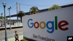 FILE - A man walks past a Google sign in San Francisco, May 1, 2019. 