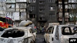 Українські рятувальники працюють у дворі п'ятиповерхового житлового будинку після ракетного обстрілу в Києві 21 березня 2024 року на тлі російського вторгнення в Україну.