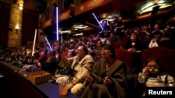 Moviegoers cheer and wave lightsabers before the first showing of the movie "Star Wars: The Force Awakens" at the TCL Chinese Theatre in Hollywood, California, Dec. 17, 2015.