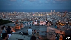 People gather outdoors at dusk on a viewpoint in Barcelona, Spain, Saturday, July 25, 2020. Britain is advising people not to travel to Spain and has removed the country from the list of safe places to visit following a surge of COVID-19 cases. (AP…