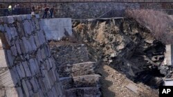 City officials and a private engineering group representatives look down at the destruction along the historic Cliff Walk on March 15, 2022 in Newport, Rhode Island. (AP Photo/Charles Krupa)