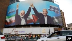 FILE - Vehicles drive past a huge banner showing the late Hamas leader Ismail Haniyeh, left, who was killed in an assassination last week, joining hands with Iranian President Masoud Pezeshkian, in a square in downtown Tehran, Iran, Aug. 5, 2024. 
