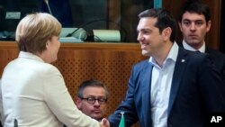 Greek Prime Minister Alexis Tsipras, right, shakes hands with German Chancellor Angela Merkel during a round table meeting at the EU-CELAC summit in Brussels on Wednesday, June 10, 2015.