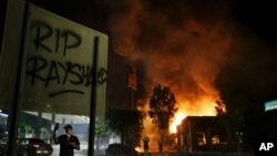 "RIP Rayshard" is spray painted on a sign as as flames engulf a Wendy's restaurant during protests Saturday, June 13, 2020, in Atlanta. The restaurant was where Rayshard Brooks was shot and killed by police Friday evening following a struggle in the…