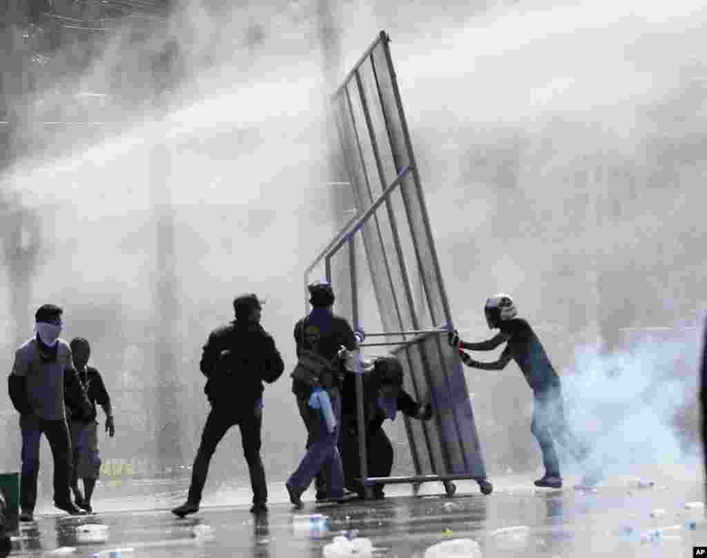 Anti-government protesters use self-made barricade against the water cannons and tear gas fired by riot police in Bangkok.