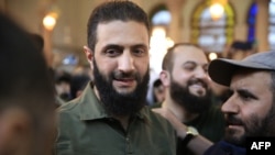 Para pendukung menyambut pemimpin kelompok Islamis Hayat Tahrir al-Sham (HTS) Suriah yang memimpin serangan merebut Damaskus dari kendali pemerintah, Abu Mohammed al-Jolani (tengah), 8 Desember 2024. (Foto: AFP)