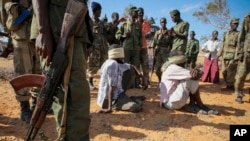 In this photo released by the African Union-United Nations Information Support Team, alleged members of al-Shabab are blindfolded and guarded at a former police station by soldiers of the Somali National Army (SNA) in Kismayo, southern Somalia, Wednesday, Oct. 3, 2012.