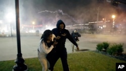 Protesters run for shelter as smoke fills the streets after the announcement of the grand jury decision not to indict police officer Darren Wilson in the fatal shooting of Michael Brown, an unarmed black 18-year-old, Nov. 24, 2014, in Ferguson, Missouri.