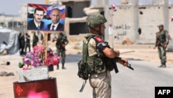 Ruski i sirijski vojnici stoje kod plakata sirijskog predsednika Bašara al-Asada i njegovog ruskog kolege Vladimira Putina u pokrajini Idlib u Siriji, 20. avgusta 2018.