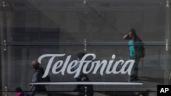 People are reflected in a glass sign of a Telefonica building in Madrid, Spain, May 13, 2017. The Spanish government said several companies including Telefonica had been targeted in ransomware cyberattack.