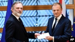 EU Council President Donald Tusk, right, gets British Prime Minister Theresa May's formal notice to leave the bloc under Article 50 of the EU's Lisbon Treaty from UK Permanent Representative to the EU Tim Barrow in Brussels, Wednesday, March 29, 2017.