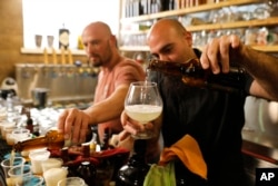Shmuel Naky, right, pours beer during a press conference in Jerusalem, Wednesday, May 22, 2019. Israeli researchers raised a glass Wednesday to celebrate a long-brewing project of making beer and mead using yeasts extracted from ancient clay vessels.