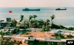 FILE - This photo released by the Military Information Agency in Taiwan shows two Taiwanese warships docking near the shore of Taiping Island, the largest of the disputed Spratly Island chain, with the Taiping military base in the foreground.