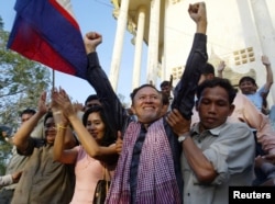 FILE - Vocal Hun Sen critic Kem Sokha raises his hands next to his wife at a temple near Prey Sar prison, 5 km (3.1 miles) west of Phnom Penh, after his release from prison January 17, 2006.