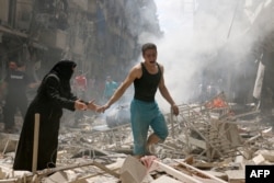 People walk amid the rubble of destroyed buildings following a reported air strike on the rebel-held neighborhood of al-Kalasa in the northern Syrian city of Aleppo, on April 28, 2016.