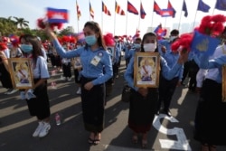 Cambodian students, holding the portrait of King Norodom Sihamoni, participate in the country's 67th Independence Day celebration, in Phnom Penh, Cambodia, Monday, Nov. 9, 2020. (AP Photo/Heng Sinith)