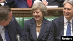 Britain's outgoing Prime Minister, David Cameron (L) speaks to incoming prime minister Theresa May and Foreign Secretary Philip Hammond, during Prime Minister's Questions in the House of Commons, July 13, 2016.