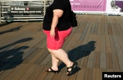 FILE - A woman walks along a boardwalk in New York.