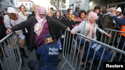 Residents of the Brussels suburb of Molenbeek are searched by police vefore taking part in a memorial gathering to honor the victims of the recent deadly Paris attacks, in Brussels, Belgium, Nov. 18, 2015.
