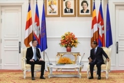 Hungarian Foreign Minister Peter Szijjarto, left, talks with Cambodian Prime Minister Hun Sen during a meeting at Peace Palace in Phnom Penh, Cambodia, Tuesday, Nov. 3, 2020. (Pool Photo via AP)