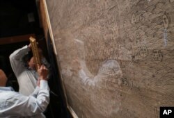 FILE - Staff hang up copies of maps dating from the Qing Dynasty purporting to back up China's claims to vast parts of the South China Sea, in Hong Kong, July. 14, 2016.
