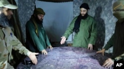 FILE - This undated photo released in 2016 shows Abu Mohammed al-Golani, second right, discussing battlefield details with field commanders over a map in Aleppo, Syria. HTS leader al-Golani has pledged to respect the rights of ethnic and religious minorities.