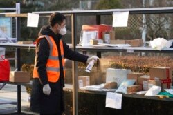 FILE - In this photo released by Xinhua News Agency, a staff member disinfects parcels at a community where a locally transmitted COVID-19 case was found, in Haidian district, Beijing, China, Jan. 18, 2022.