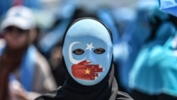 A demonstrator wearing a mask painted with the colours of the flag of East Turkestan and a hand bearing the colours of the Chinese flag attends a protest of supporters of the mostly Muslim Uighur minority and Turkish nationalists to denounce China's treat