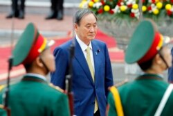 Japanese Prime Minister Yoshihide Suga reviews an honor guard at the Presidential Palace in Hanoi, Vietnam Monday, Oct. 19, 2020. Suga is on an official visit to Vietnam. (AP Photo/Minh Hoang, Pool)