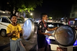 រូបឯកសារ៖ បុរសពីរនាក់គោះថាសដែកជាសញ្ញាចូលរួមប្រឆាំងរដ្ឋប្រហារយោធា នៅទីក្រុងរ៉ង់ហ្គូន មីយ៉ាន់ម៉ា កាលពីថ្ងៃទី៤ ខែកុម្ភៈ ឆ្នាំ២០២១។