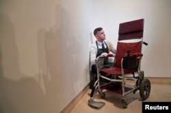 Fine-art handler Tom Richardson poses with a motorised wheelchair belonging to British theoretical physicist Stephen Hawking ahead of an auction of items from Hawkings' personal estate at Christie's in London, Britain, Oct. 30, 2018.