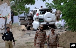 Pakistani security officials stand guard at the site of a suicide bombing which killed dozens of people and left many injured in Mastung district near Quetta, Pakistan, May 12, 2017.