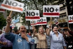 People holding signs with a message that reads in Spanish: "No more dictatorship" take part in a walkout against President Nicolas Maduro, in Caracas, Venezuela, Jan. 30, 2019.