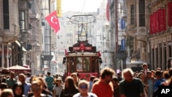 FILE - People walk in central Istanbul's Istiklal Avenue, the main shopping road of Istanbul, in this photo dated Wednesday, Aug. 22, 2018. Tourists have returned in droves to Turkey, helped this summer by the sharp fall in the value of the Turkish lira following economic uncertainty and a rift with the United States.