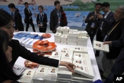 Attendees pick up copies of a book on the governance of Chinese President Xi Jinping at the media center for the Second Belt and Road Forum In Beijing on April 26, 2019.